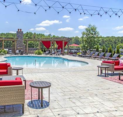 A pool area with red couches and a stone fireplace.